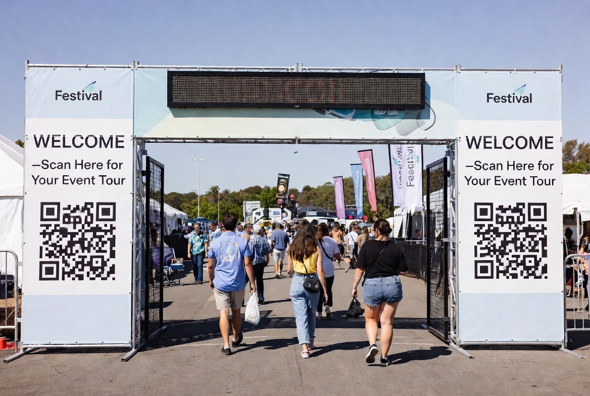 A festival entrance gate with WELCOME — Scan Here for Your Event Tour panels and QR codes as guests walk in