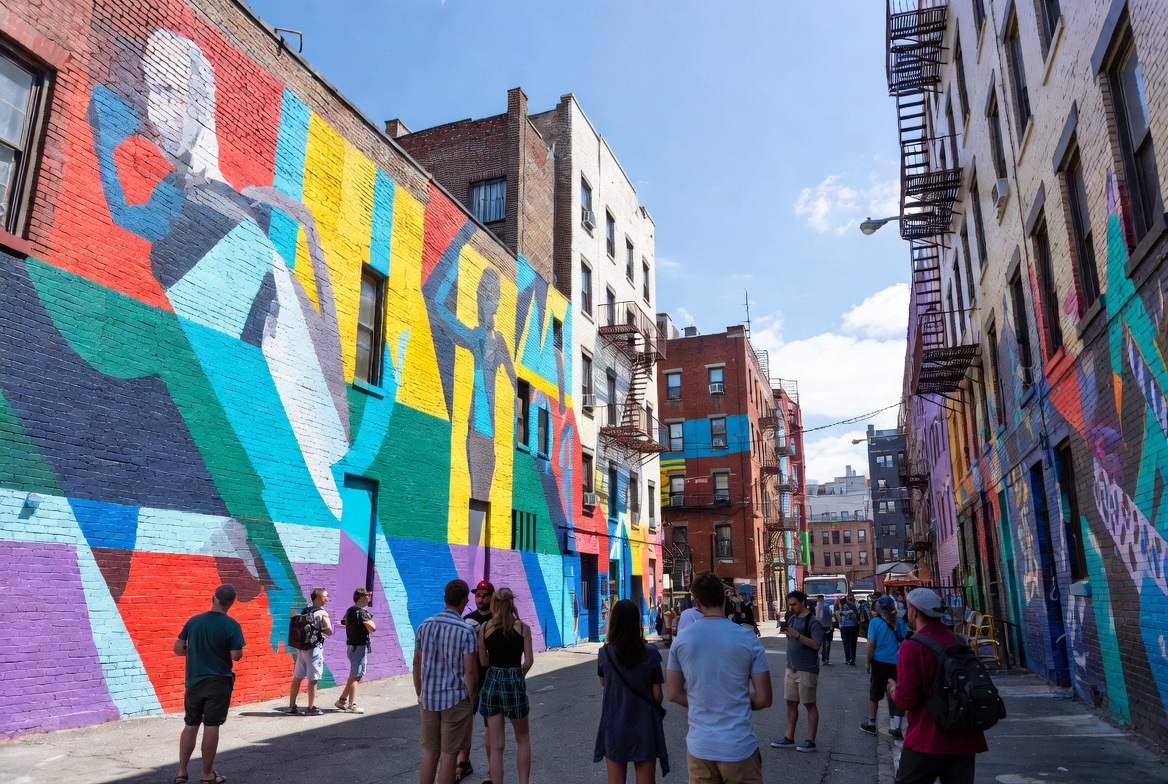 Visitors walking a narrow street lined with vivid building-scale murals